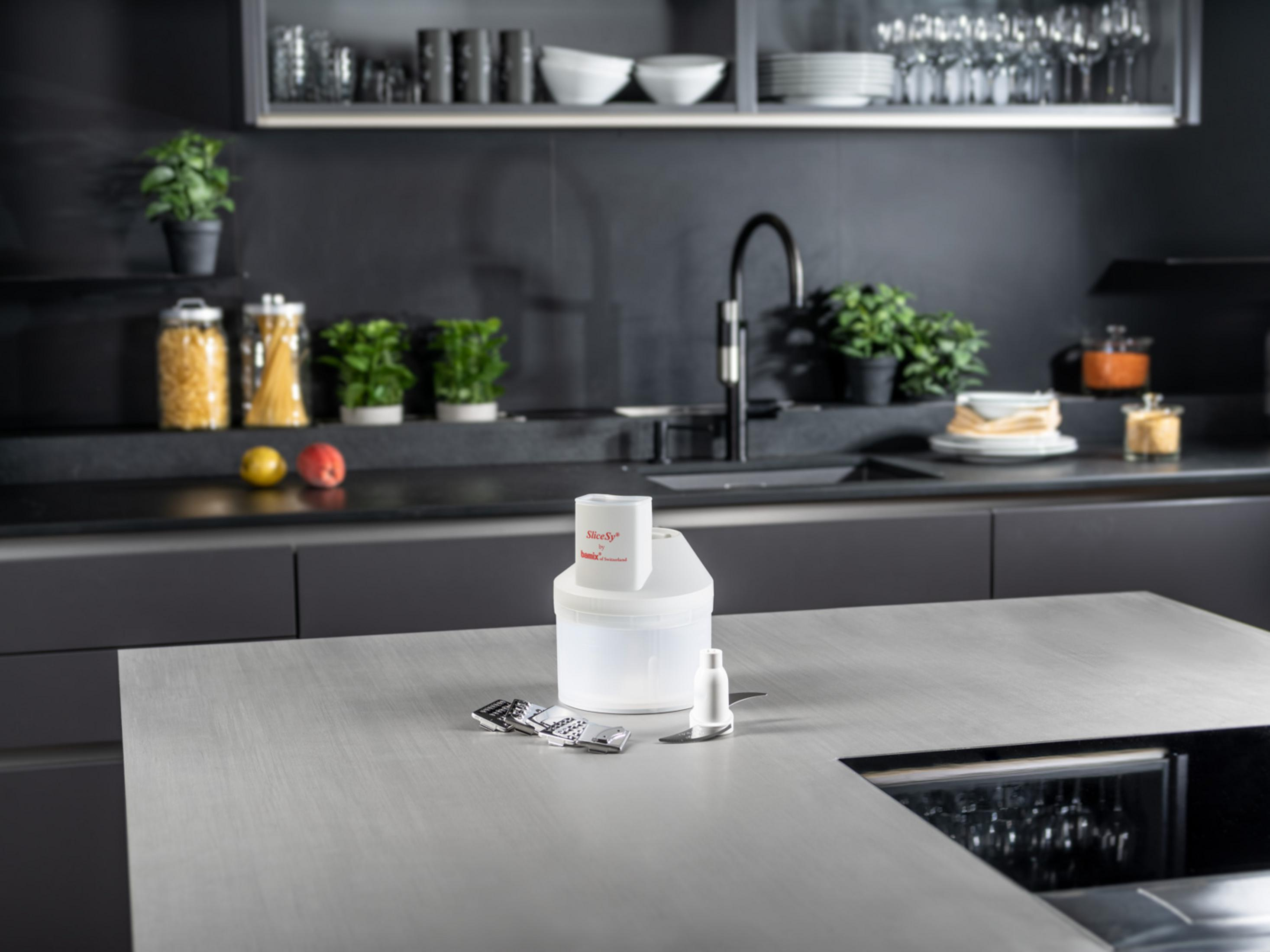 Une trancheuse de cuisine blanche avec accessoires est posée sur un plan de travail.