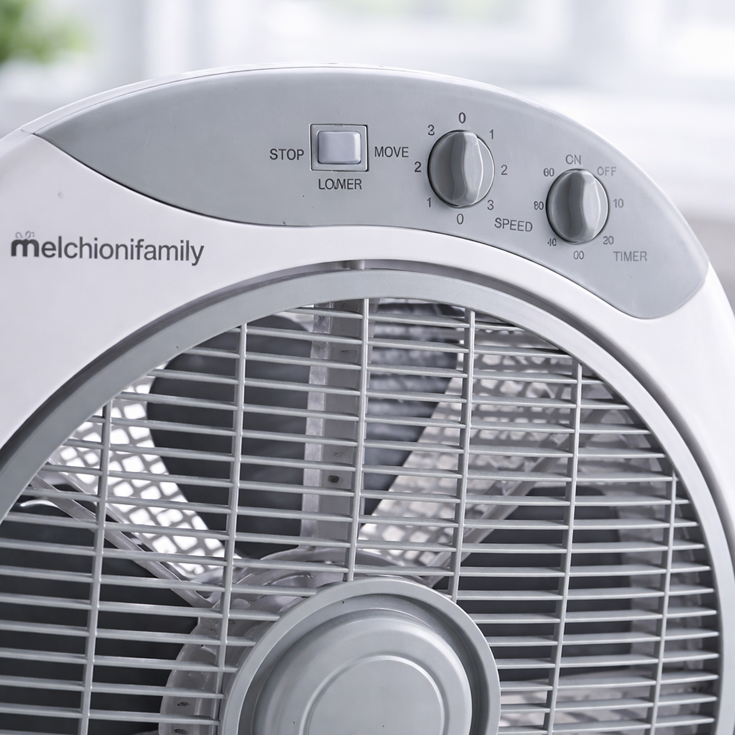 Ventilador de caja blanco con controles grises: STOP, MOVE, SPEED, TIMER. Logo Melchionifamily.