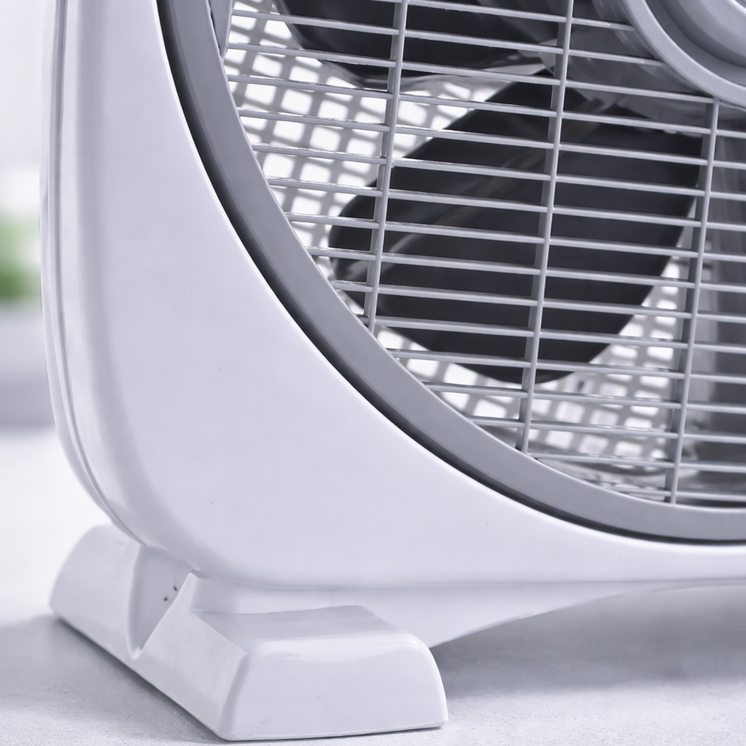 Primer plano de un ventilador de caja blanco con rejilla gris y aspas negras.