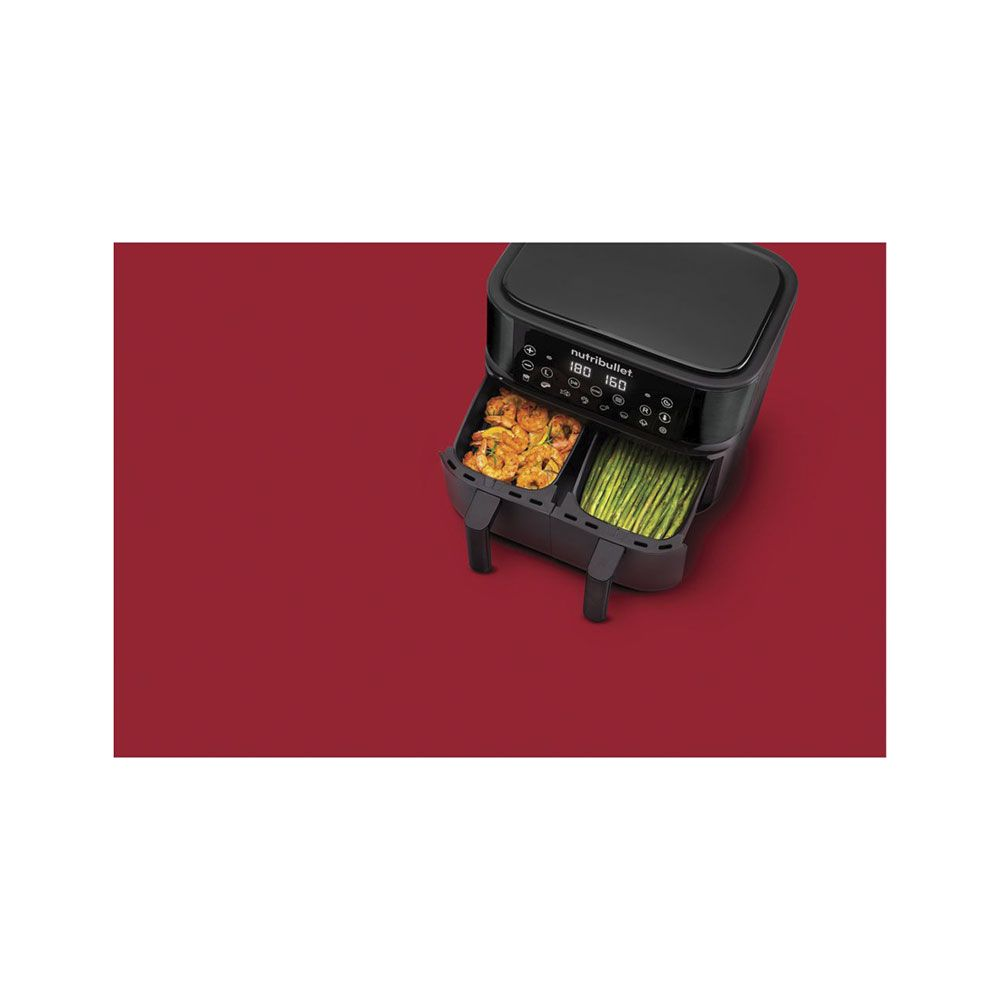 Une friteuse à air noire à double panier avec crevettes et asperges.