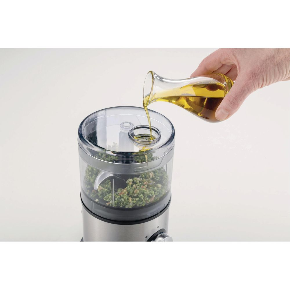 L'olio viene versato in un robot da cucina con ingredienti.