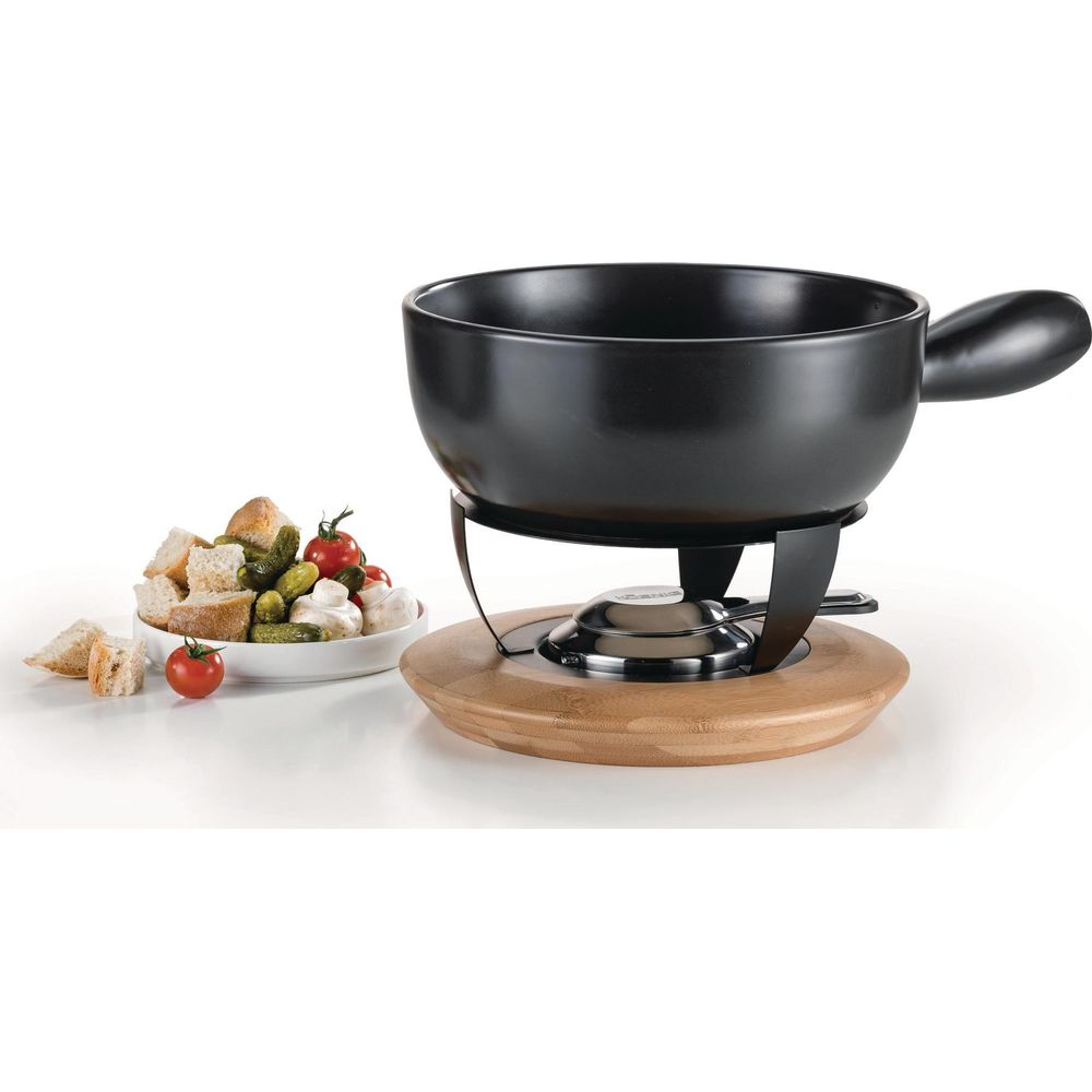 Schwarzes Fondue-Set mit Holzsockel, gefüllter Schüssel mit Brot und Gurken.