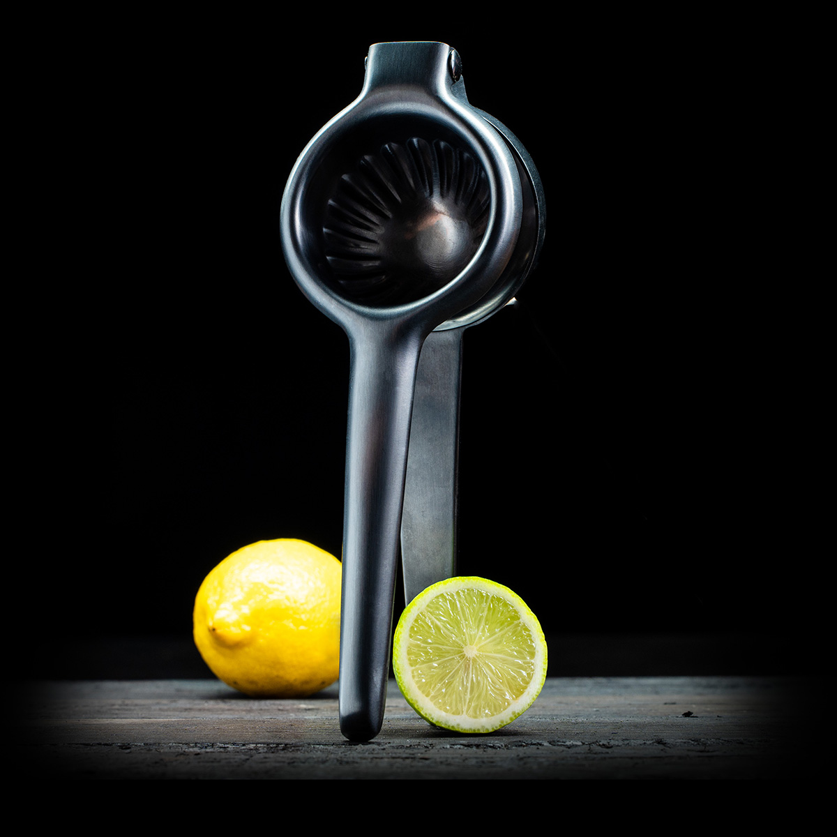 Un spremiagrumi in metallo con un limone intero e mezzo su un tavolo di legno.