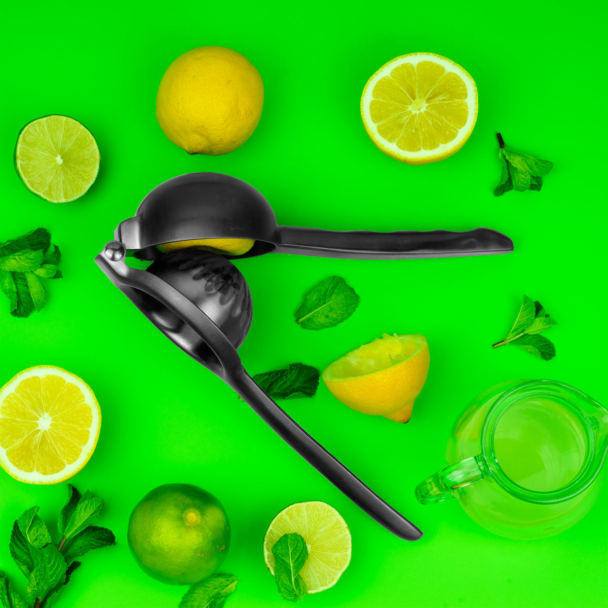 Un spremiagrumi nero con limoni, lime, menta e succo su sfondo verde.