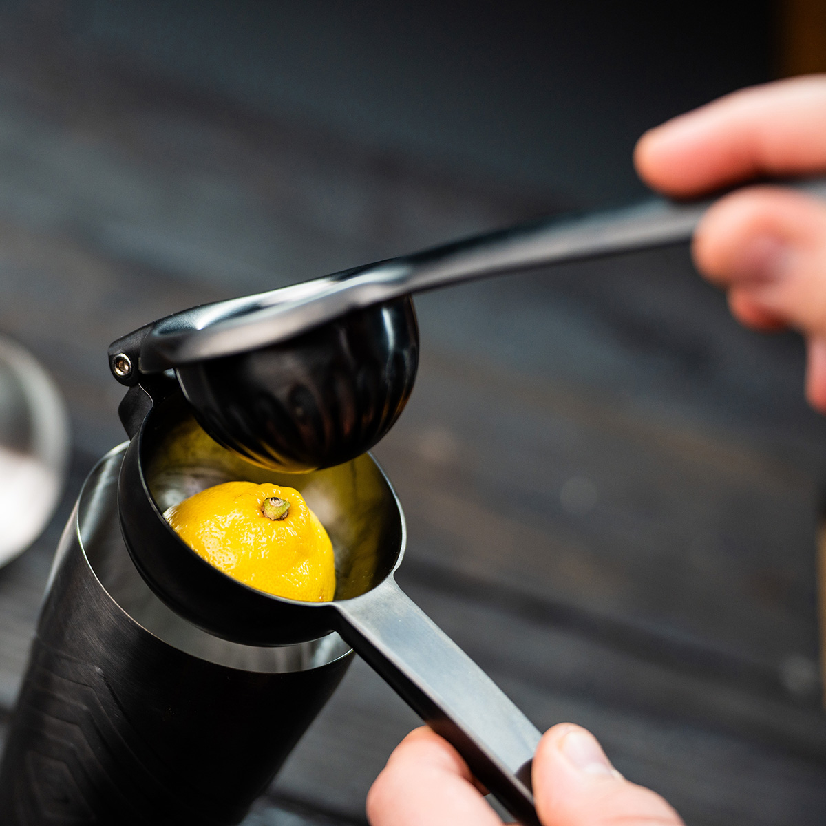 Una mano usa uno spremiagrumi per spremere mezzo limone in una tazza.