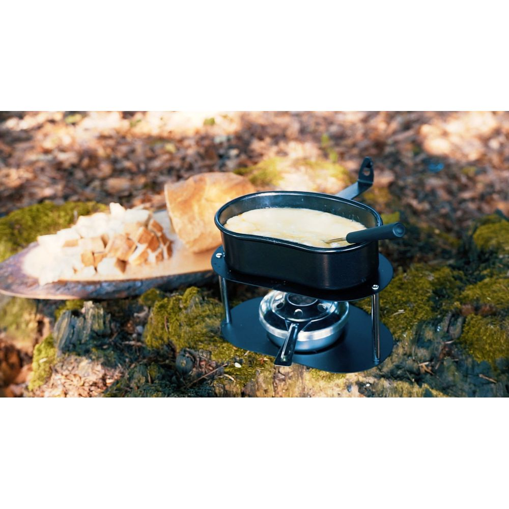 Ein Käsefondue-Set mit Brotstücken auf einem Baumstumpf im Wald.