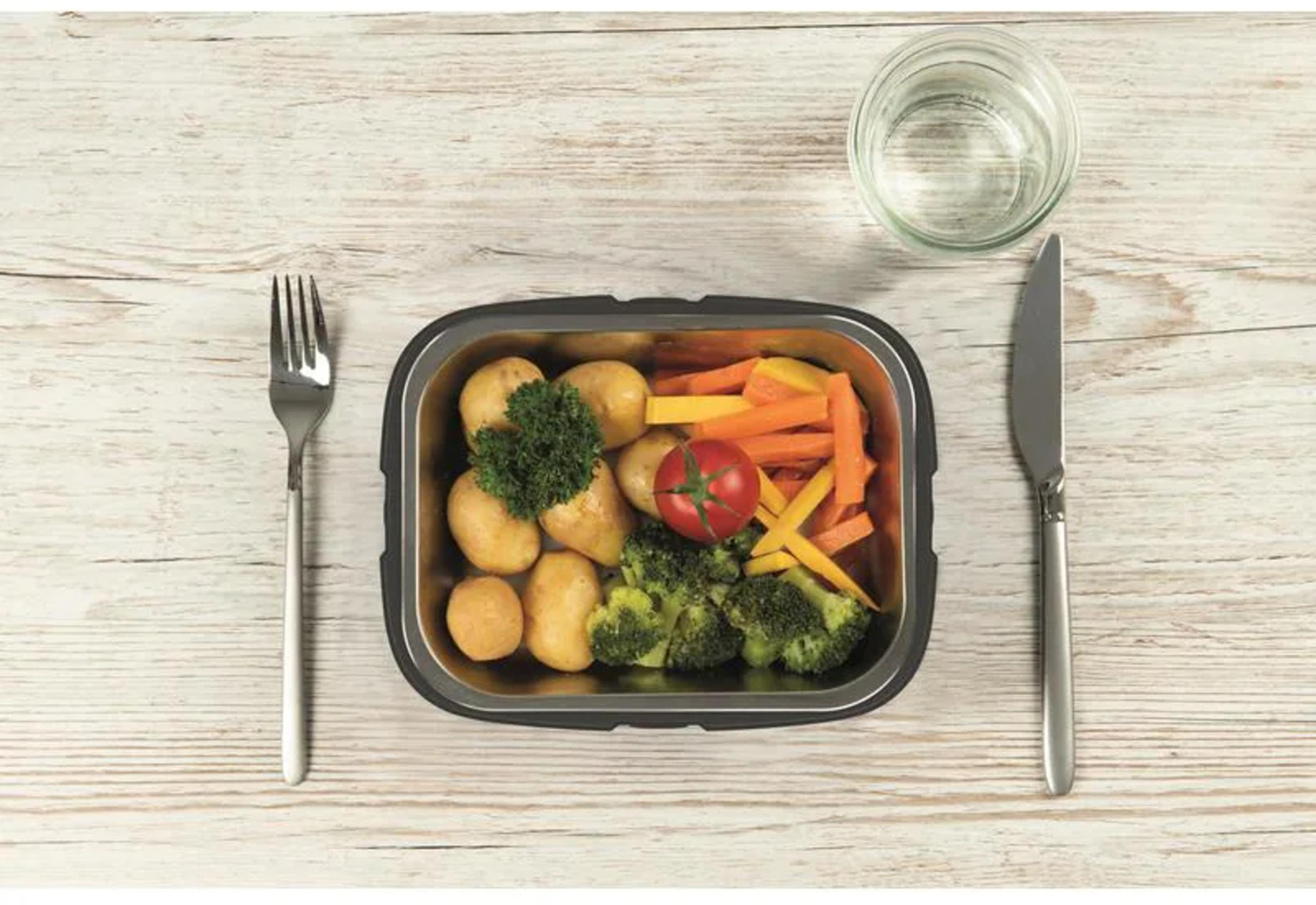 Ein Teller mit Kartoffeln, Brokkoli, Karotten und Tomaten. Gabel und Messer daneben.
