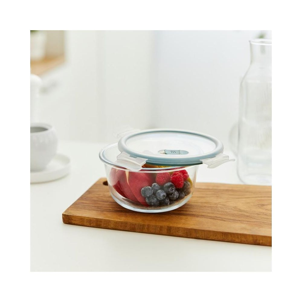 Contenitore di vetro con frutta, su tagliere di legno.