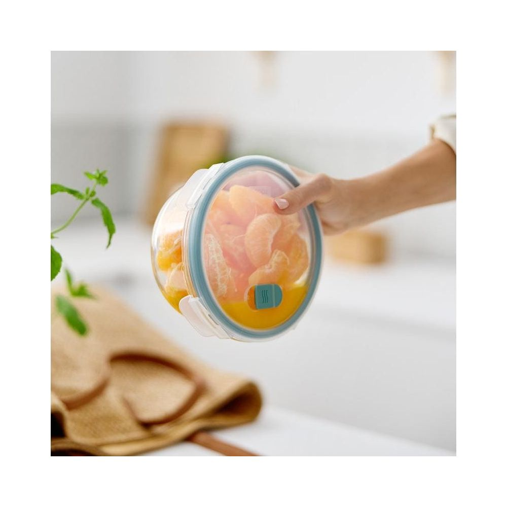 Una mano tiene un contenitore trasparente pieno di spicchi d'arancia e succo.