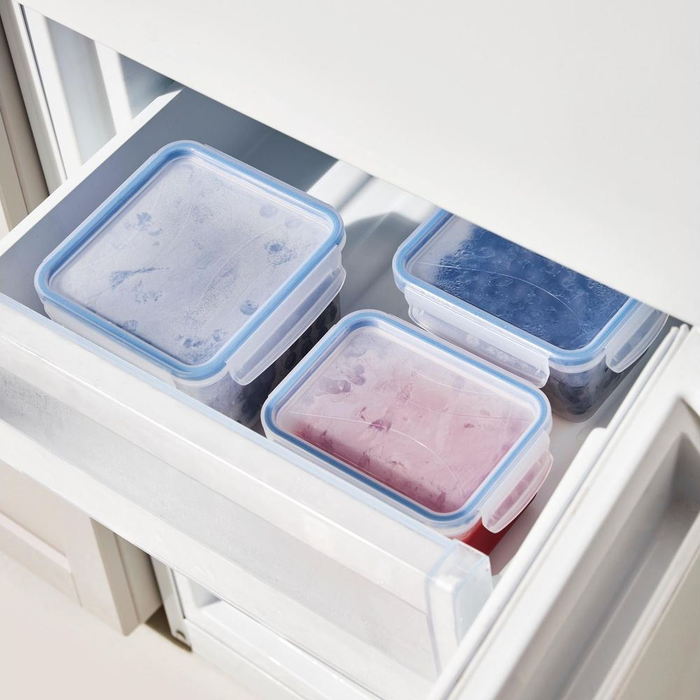 Tre contenitori trasparenti con cibo congelato in un cassetto del frigorifero.