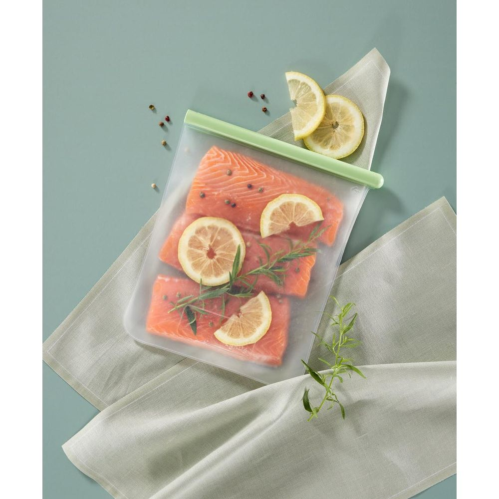 Roher Lachs in einer wiederverschließbaren Tasche mit Zitronenscheiben und Kräutern.