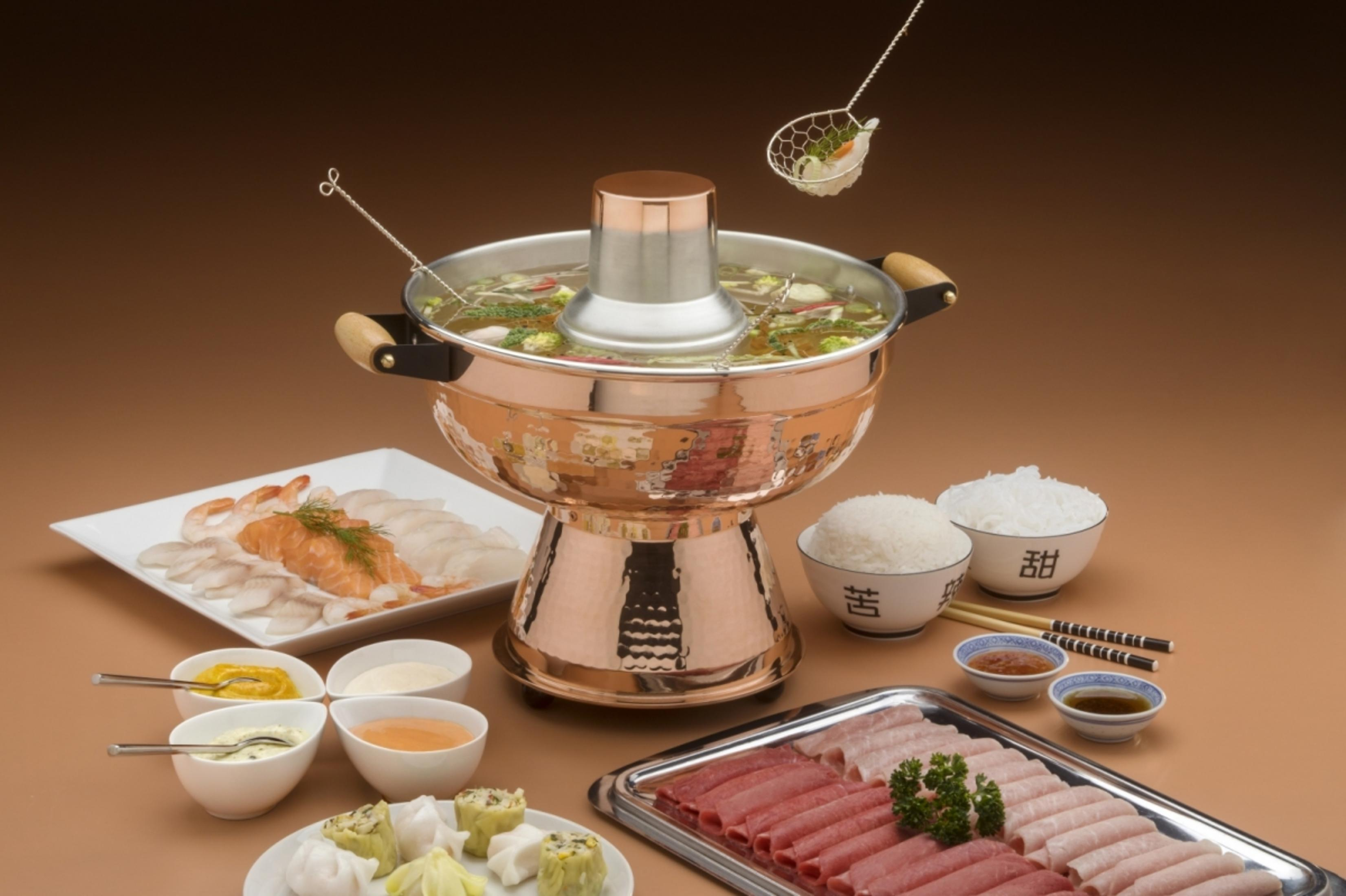 Ein Hotpot mit Zutaten wie Fisch, Garnelen, Fleischscheiben, Reis und Dips.