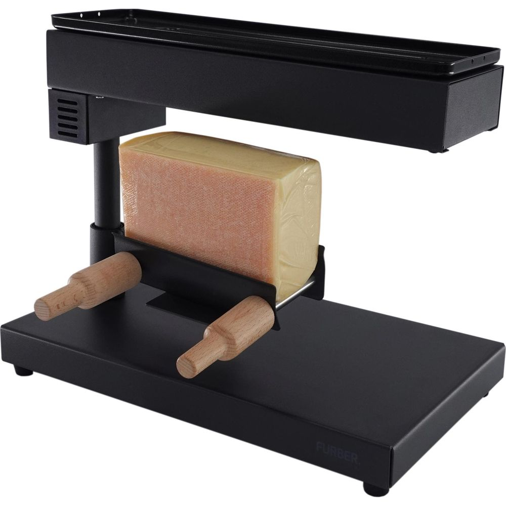 Ein schwarzer Raclette-Grill mit einem Block Käse, der zum Schmelzen bereit ist.