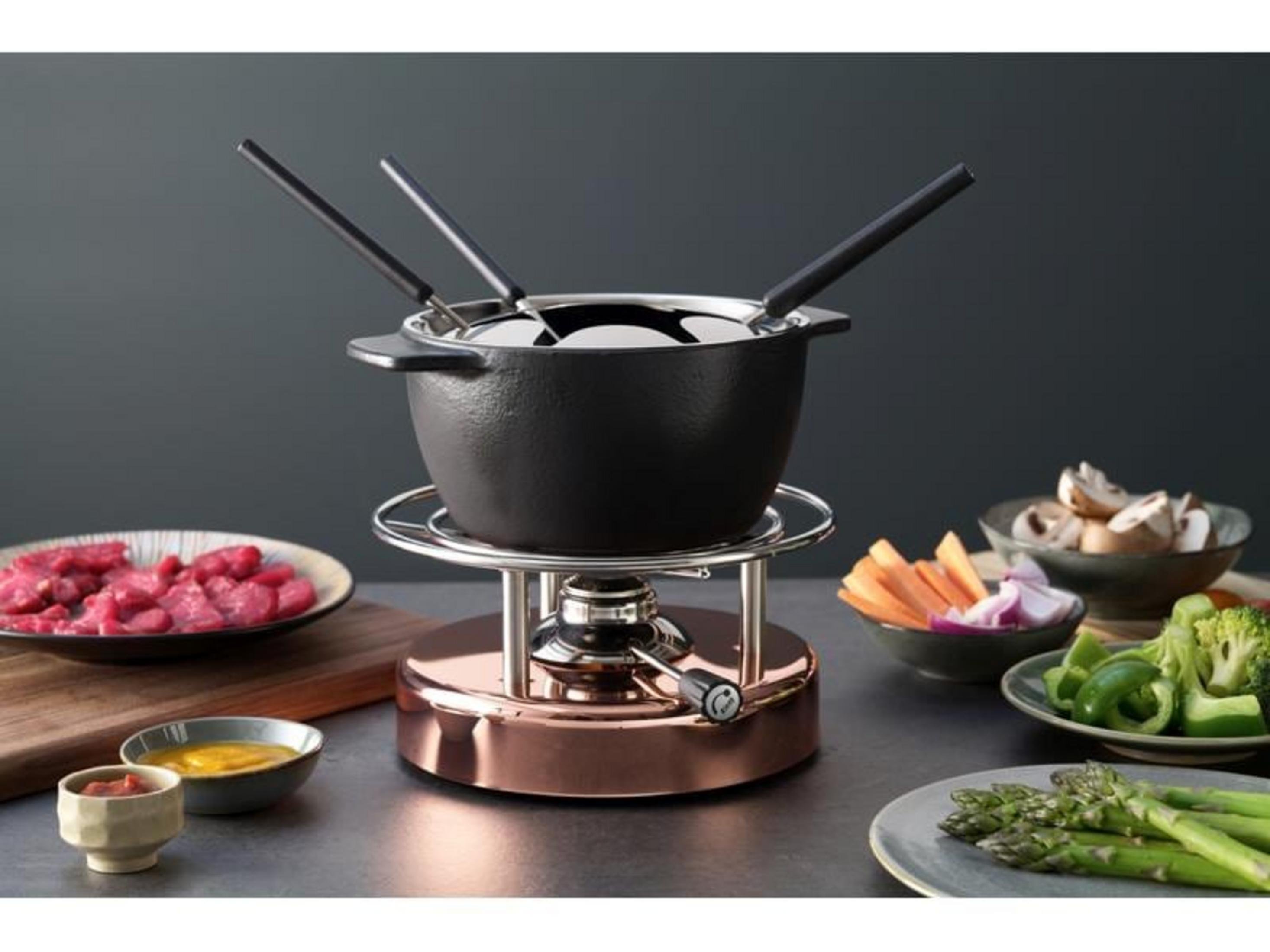 Fondue-Set mit schwarzem Topf, Fleisch, Gemüse und Dips auf Tisch.