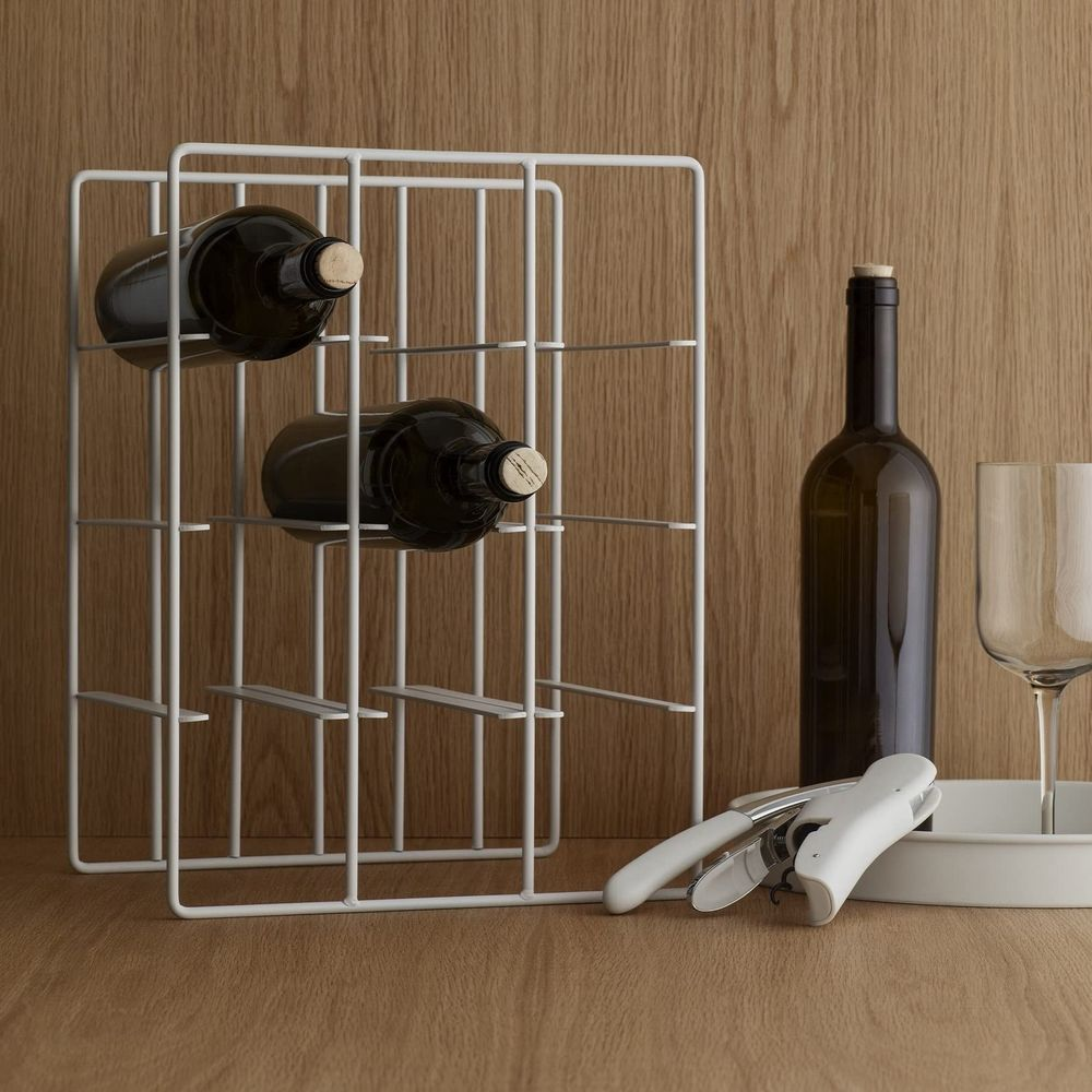 Weißer Weinregal mit zwei Flaschen, einer einzelnen Flasche, Glas und Korkenzieher auf Holz.