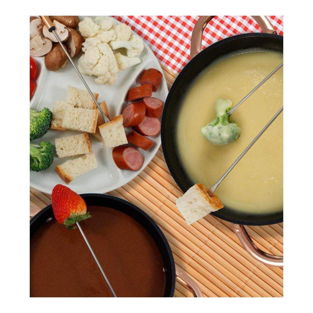 Zwei Fonduetöpfe mit Brot, Wurst, Brokkoli, Blumenkohl und Erdbeeren auf einem Teller.