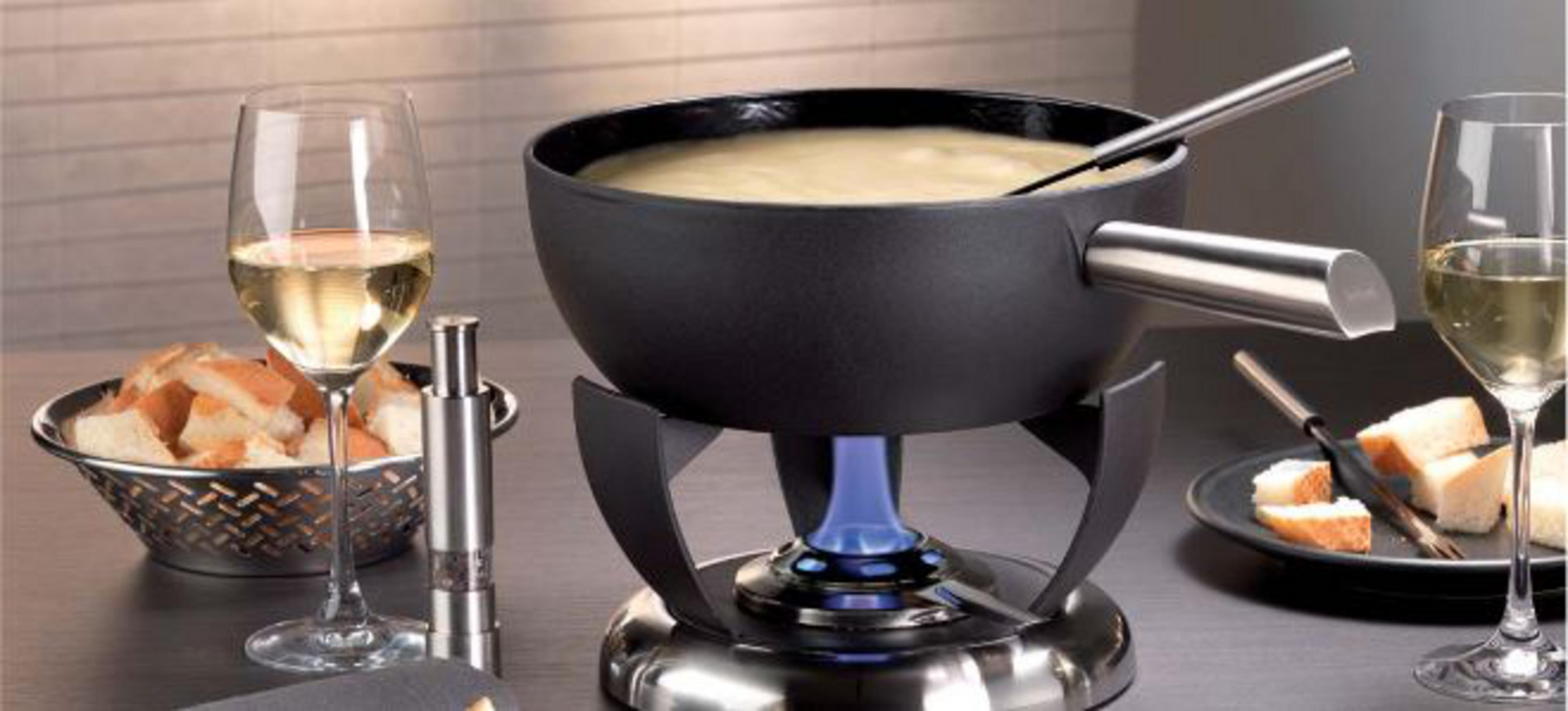 Ein Käsefondue-Topf mit Brotstücken, Wein und einem Brenner.