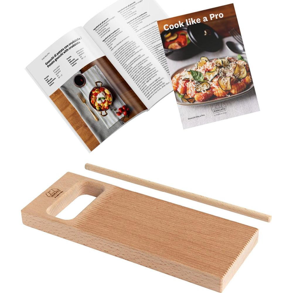 Une planche à gnocchi en bois et un rouleau à pâtisserie se trouvent sous un livre de cuisine ouvert avec des recettes et des photos.