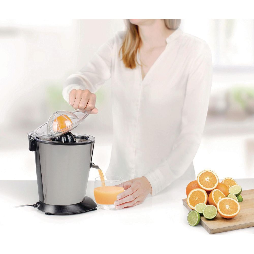 Una donna usa uno spremiagrumi per spremere succo d'arancia in un bicchiere.