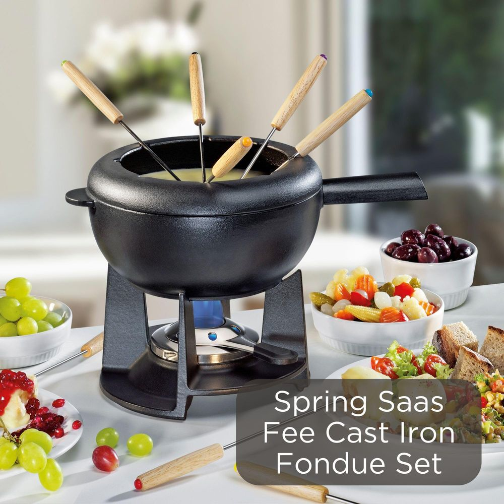 Ein schwarzes Gusseisen-Fondue-Set mit Käse, Brot, Obst und Gemüse.