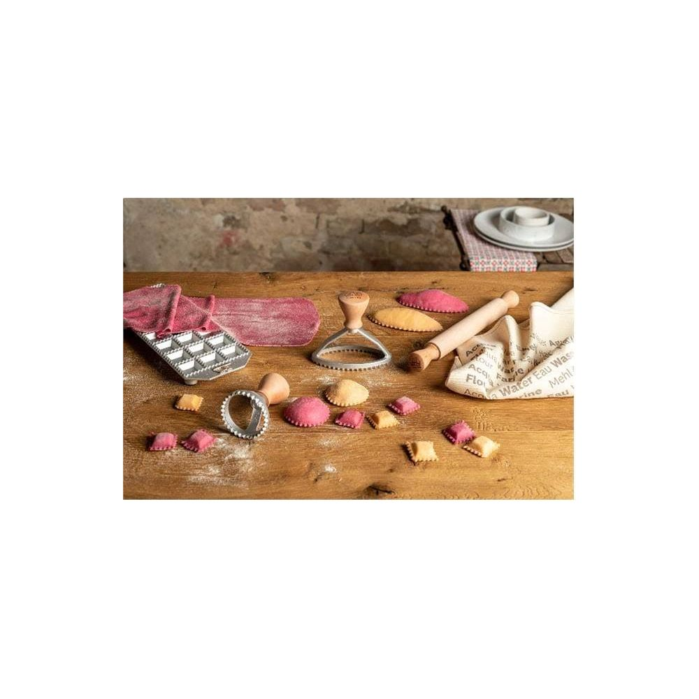 Outils de fabrication de pâtes et pâtes farcies sur une table en bois.