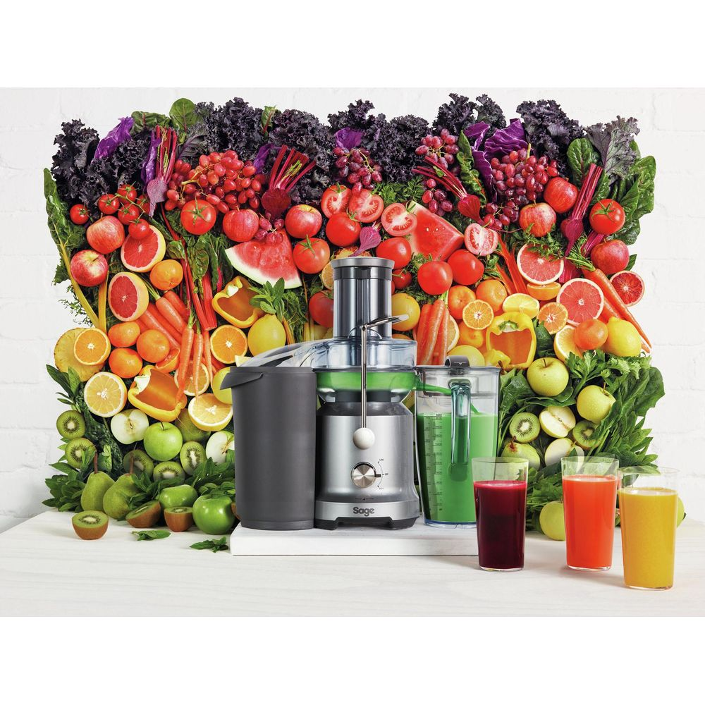 Un estrattore di succo davanti a un display vibrante di frutta e verdura.