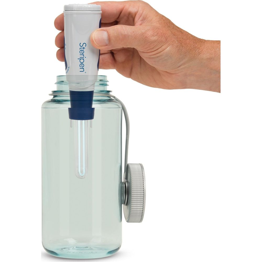 Eine Hand hält einen SteriPEN über eine blaue Wasserflasche.