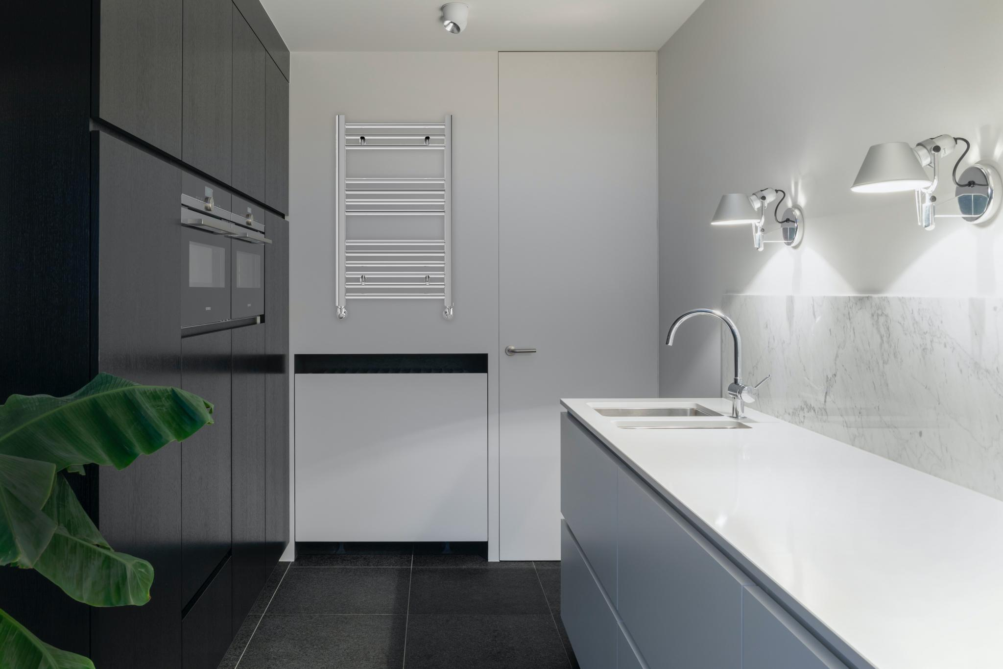 Cocina moderna con gabinetes oscuros, horno doble, fregadero y toallero de pared.