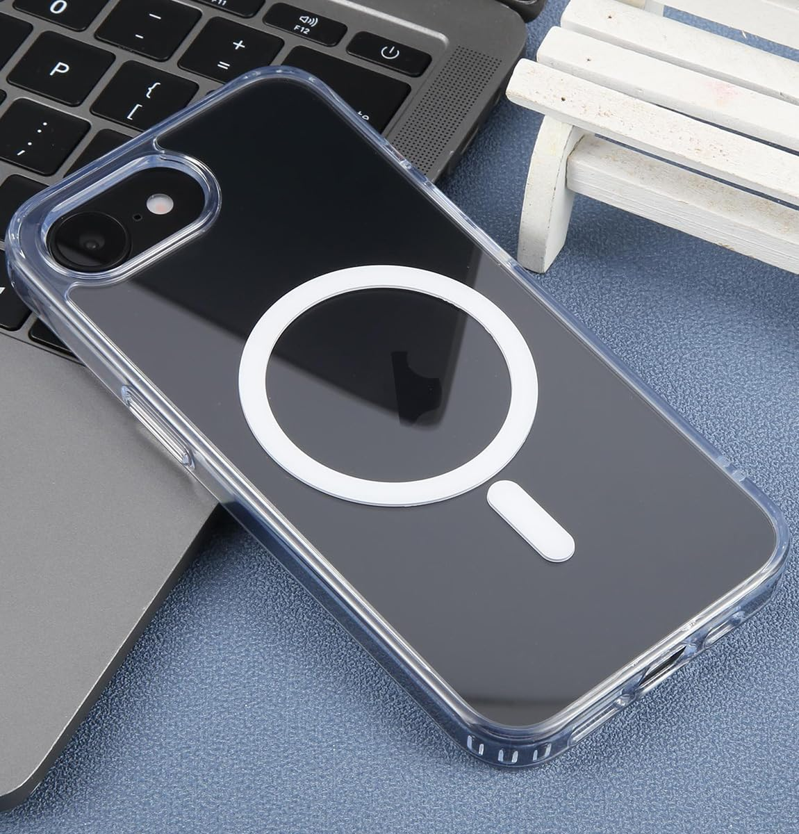 Una funda transparente para teléfono con anillo magnético blanco está sobre un teclado de portátil.
