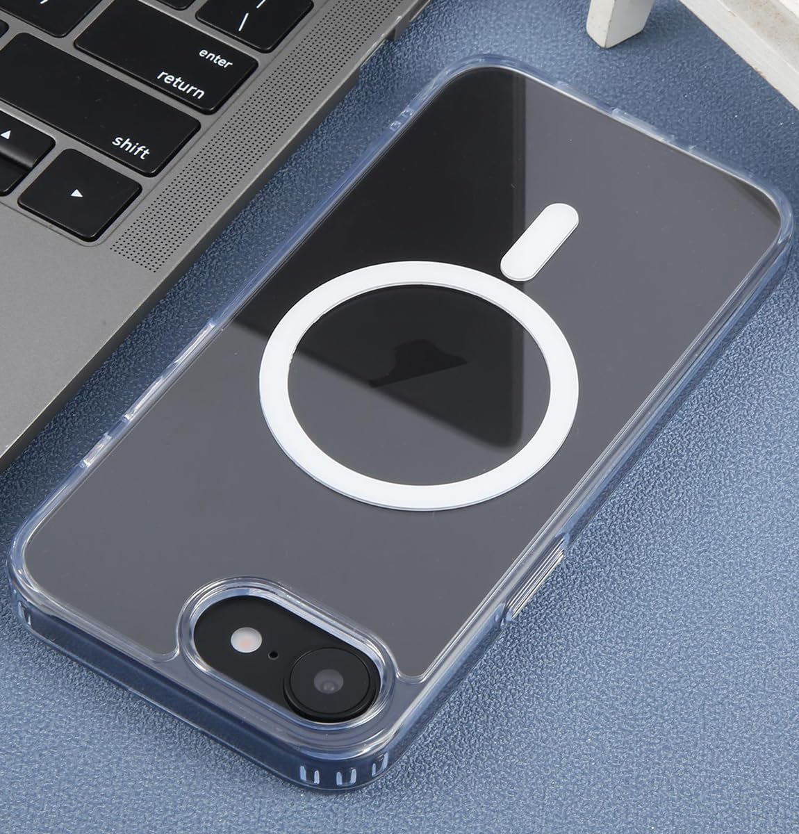 Una funda de teléfono transparente con anillo magnético blanco y óvalo en un teclado de portátil.