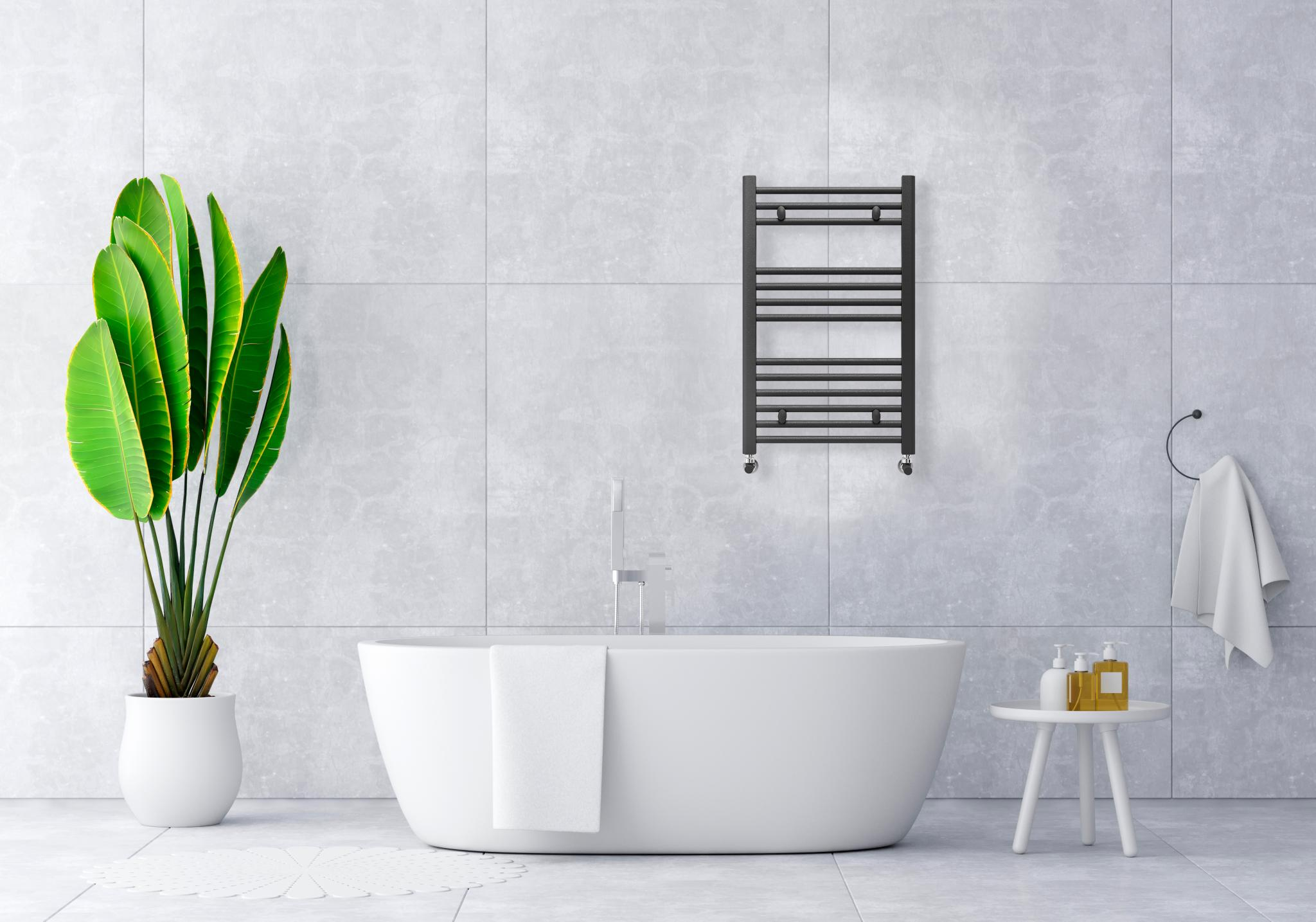 Baño moderno con bañera exenta, plantas y toallero calefactor.