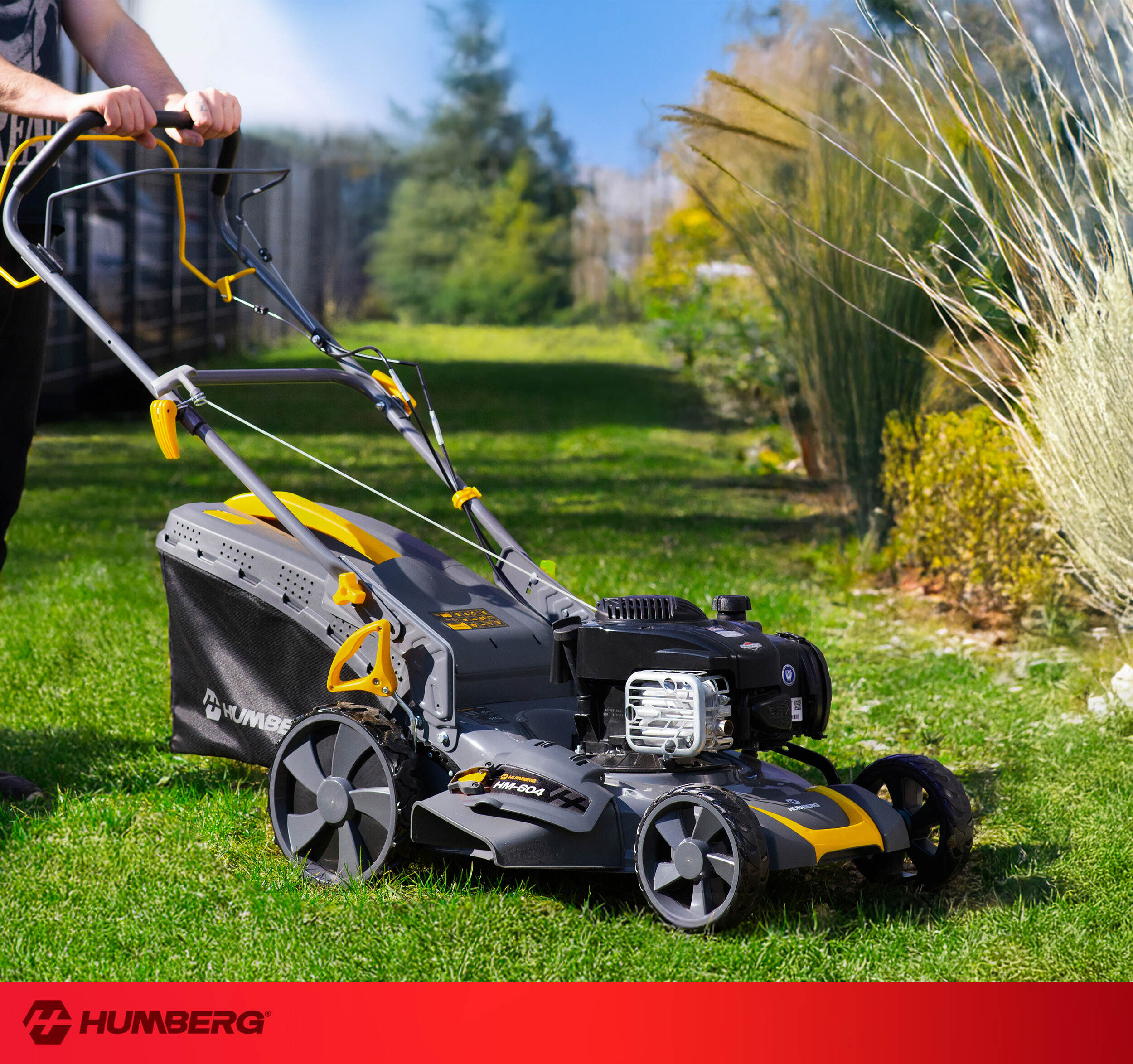 Osoba pchająca szaro-żółtą kosiarkę po zielonym trawniku.