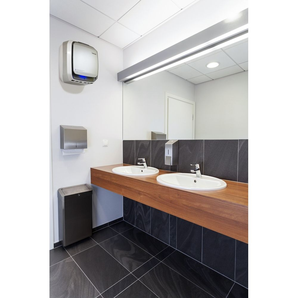 Bagno moderno con due lavandini, dispenser asciugamani di carta, cestino e asciugamani.