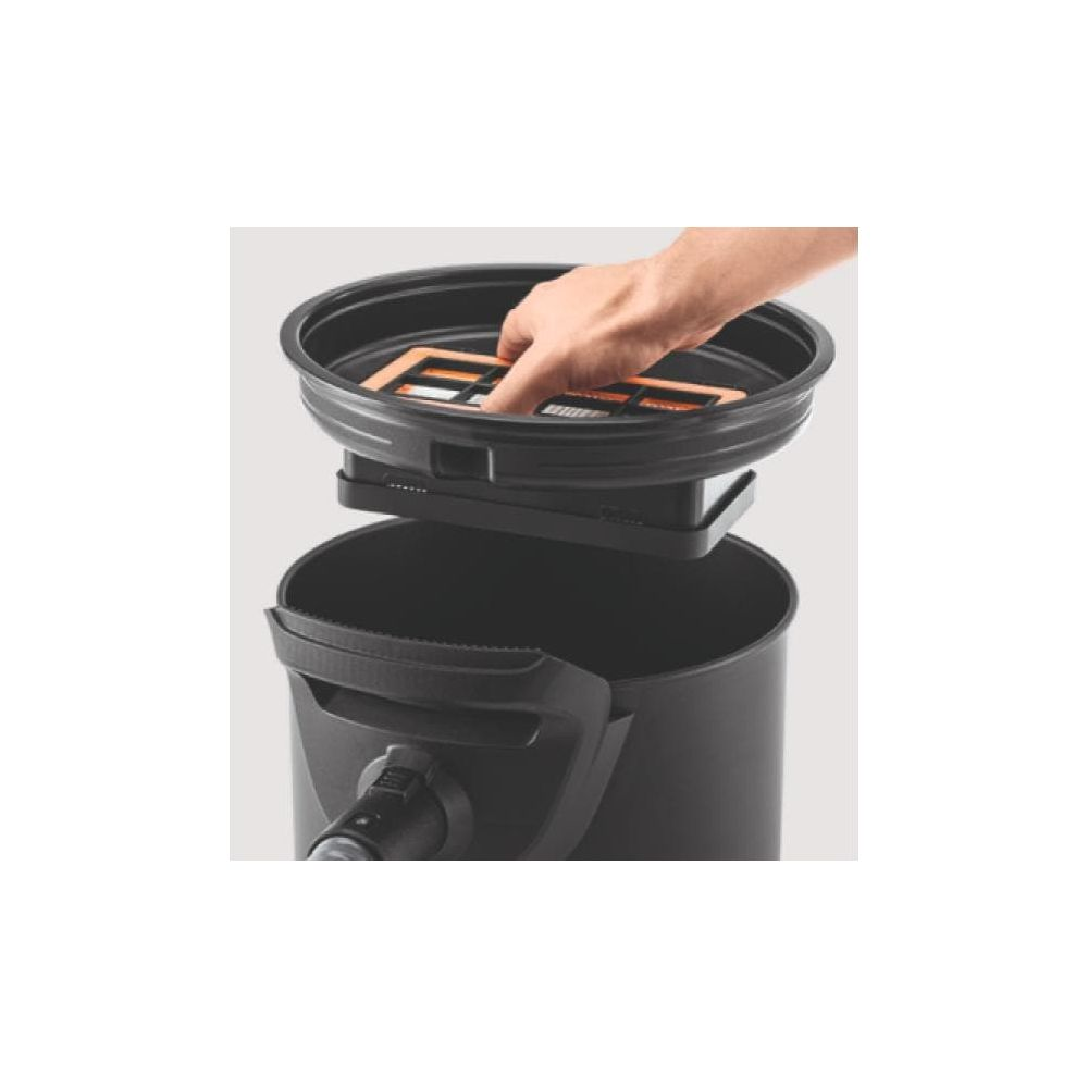 Eine Hand setzt einen orangefarbenen Filter in einen schwarzen Staubsaugerbehälter ein.