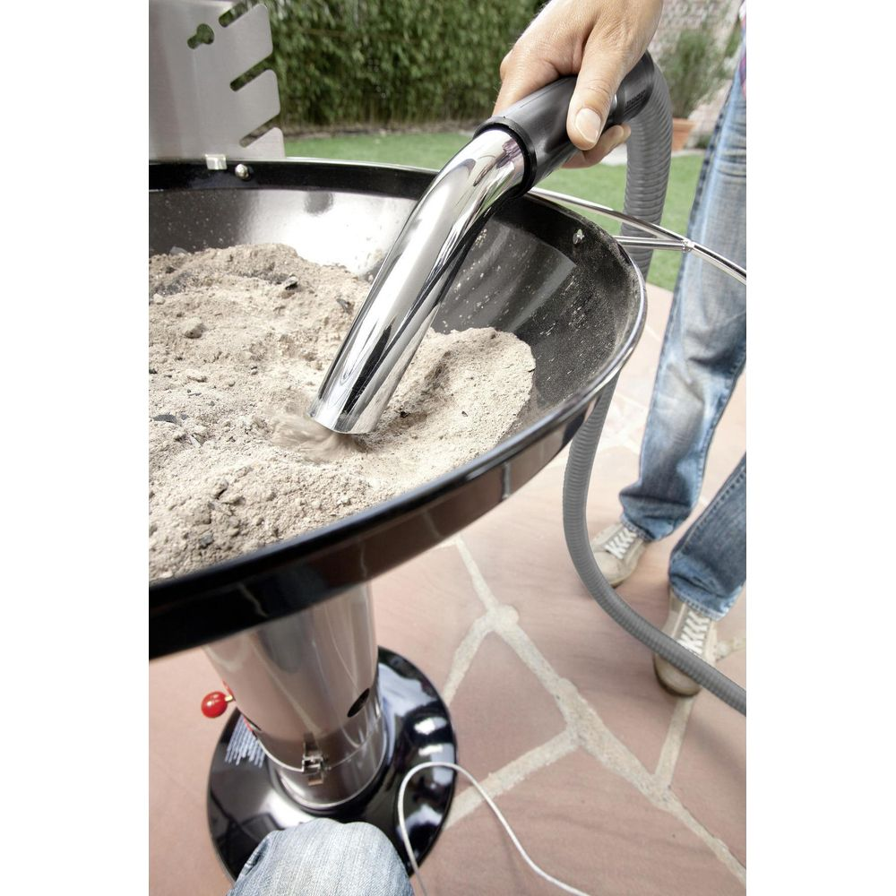 Ein Mann saugt Asche aus einem Grill mit einem speziellen Staubsauger.