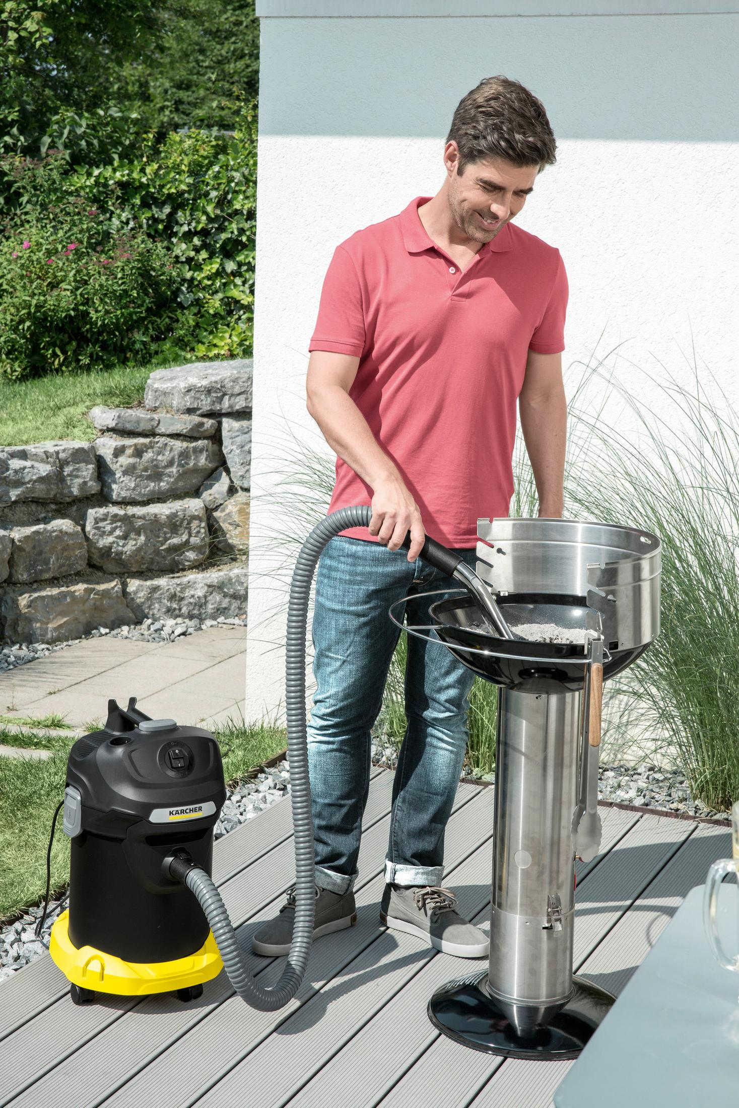 Mann saugt Grillasche mit Kärcher Sauger aus Edelstahl-Grill.