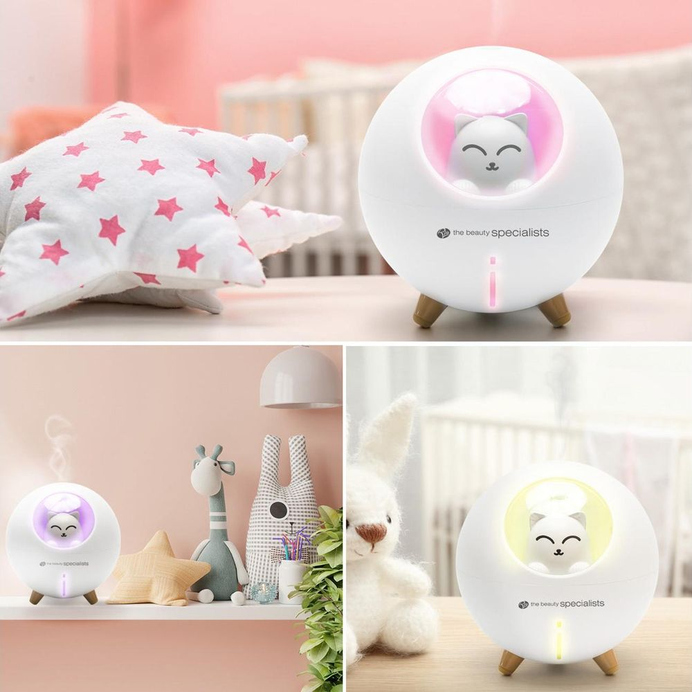 Un diffusore bianco a forma di gatto con luci rosa e gialle su uno scaffale con giocattoli.
