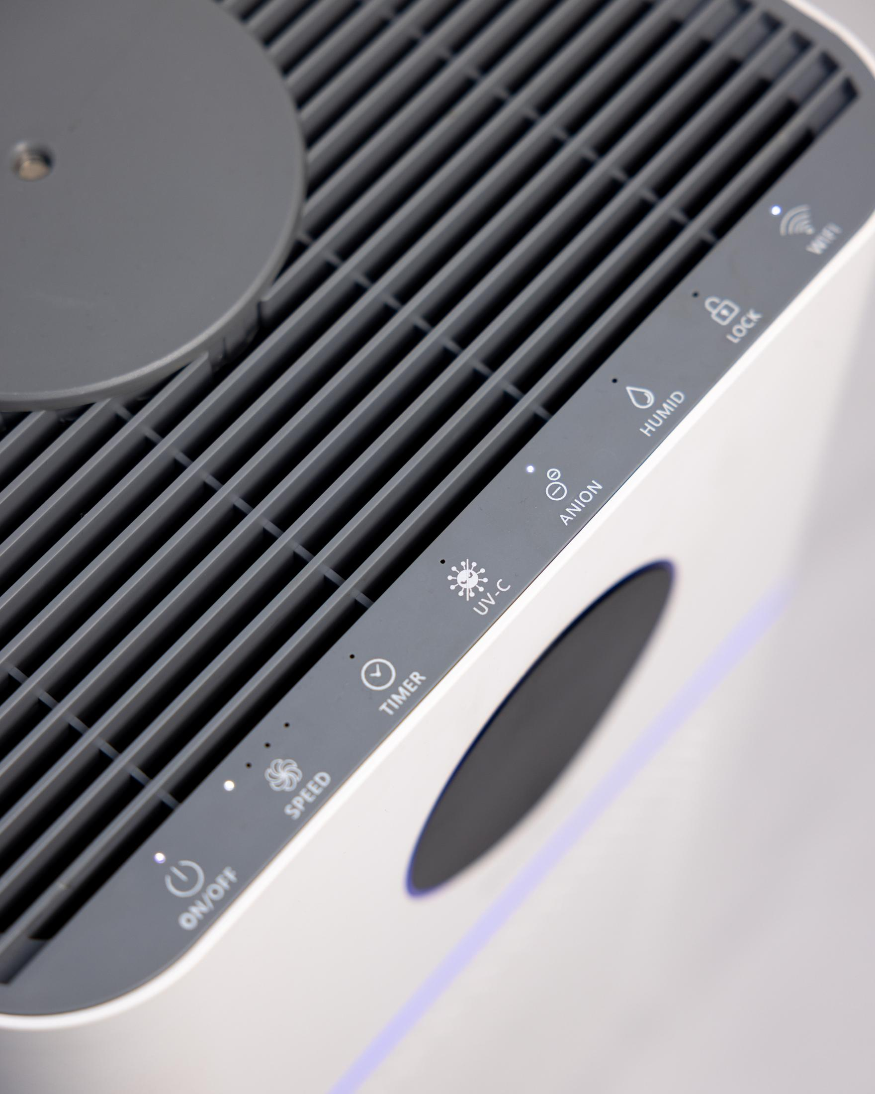 Primo piano di un purificatore d'aria bianco con prese d'aria e pulsanti grigi.
