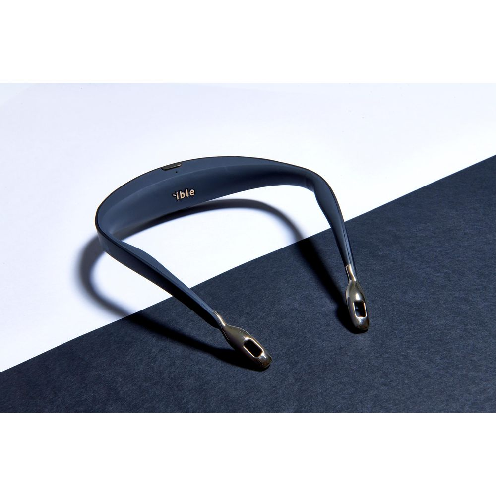 Casque tour de cou gris foncé avec accents dorés sur surface noire et blanche.