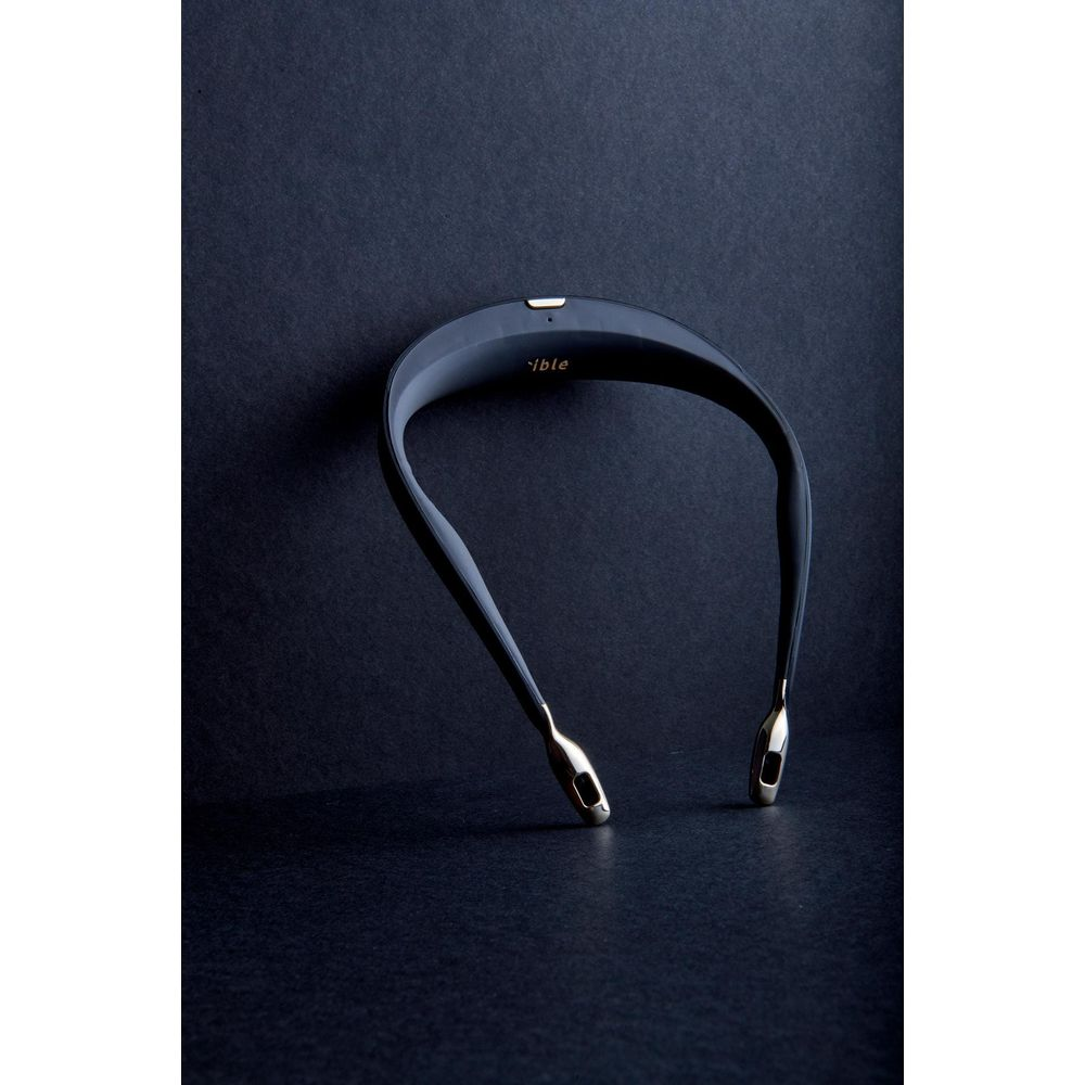 Un casque tour de cou noir avec des embouts dorés repose sur un fond sombre.