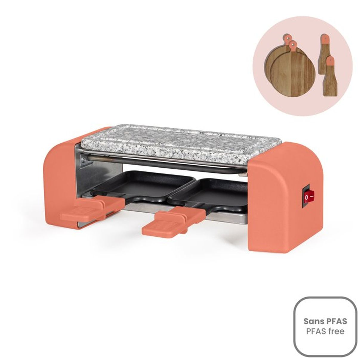 Ein korallenfarbener Raclettegrill mit Steinplatte und zwei Pfannen.