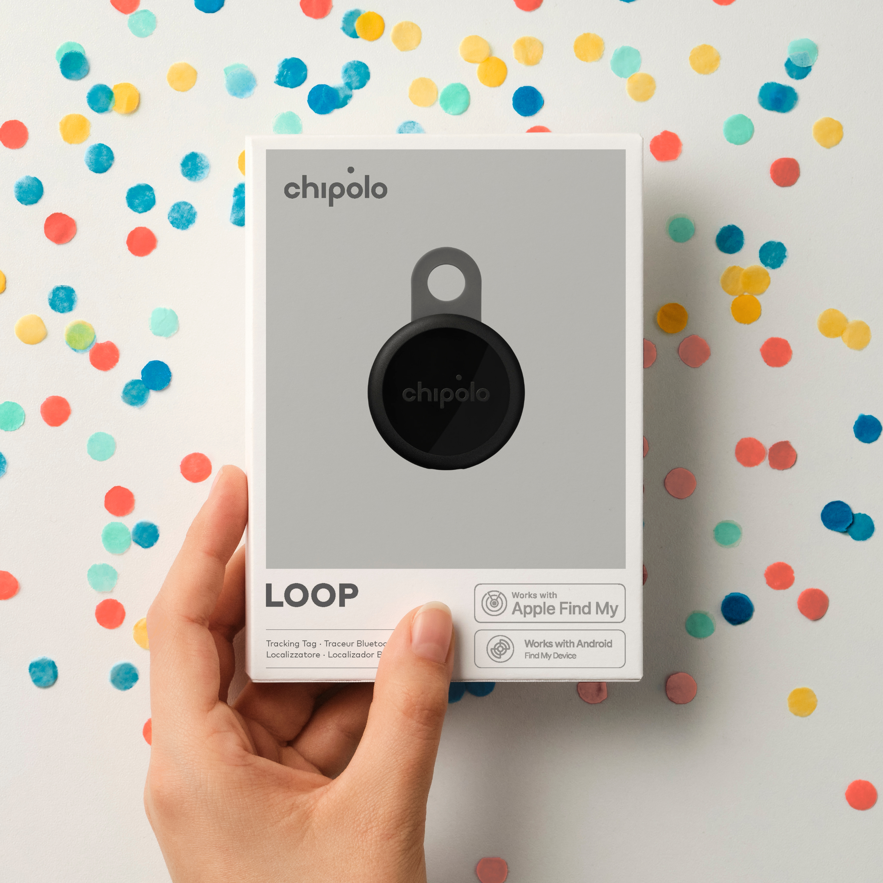 Chipolo LOOP Tag de Suivi en Boîte, tenu par la main, avec confettis.