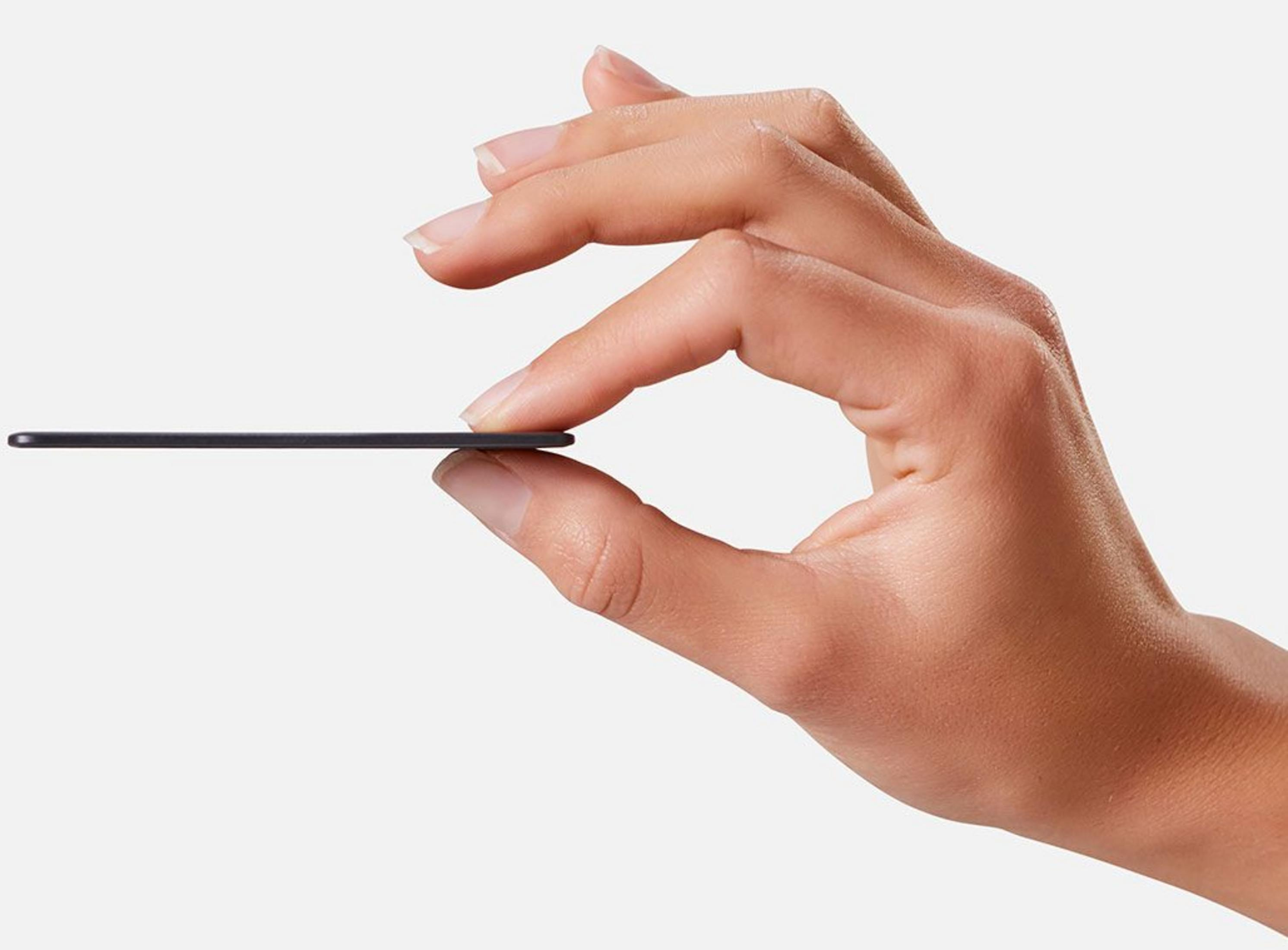 A hand holds a thin black object between thumb and forefinger.