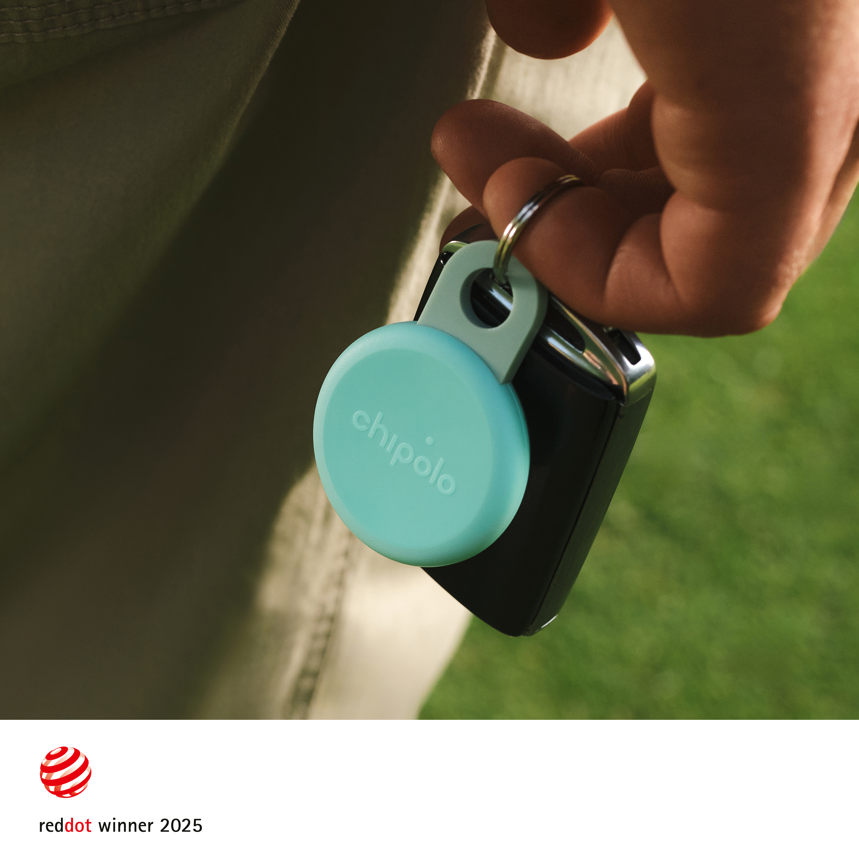 A hand holds keys with a mint green Chipolo tracker attached.