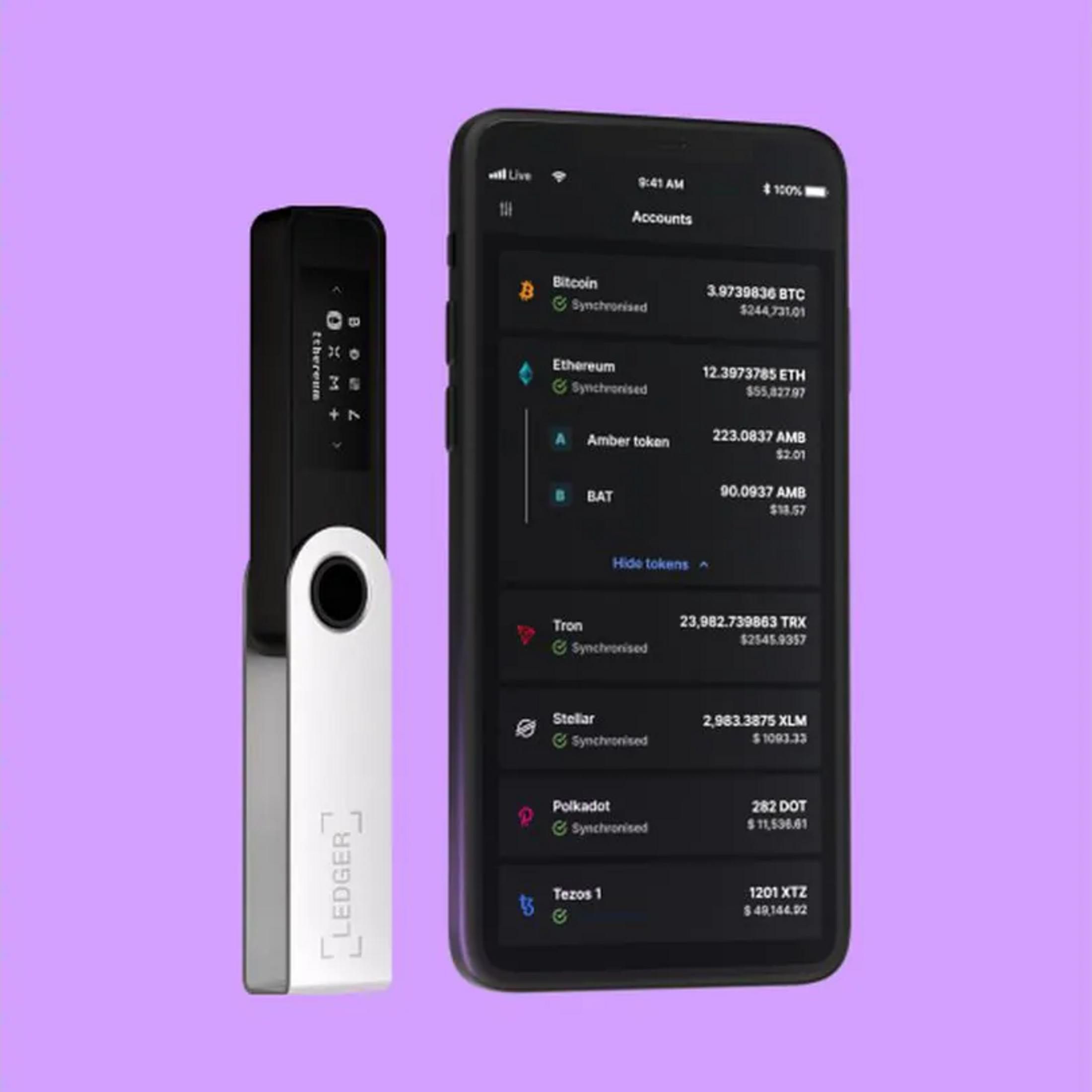Portfel sprzętowy Ledger obok smartfona wyświetlającego portfolio kryptowalut z Bitcoinem, Ethereum i innymi aktywami cyfrowymi.