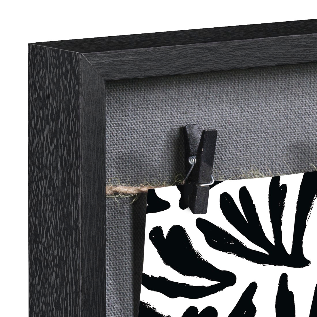 Un cadre noir avec fond de tissu gris et une pince à linge tenant une image.
