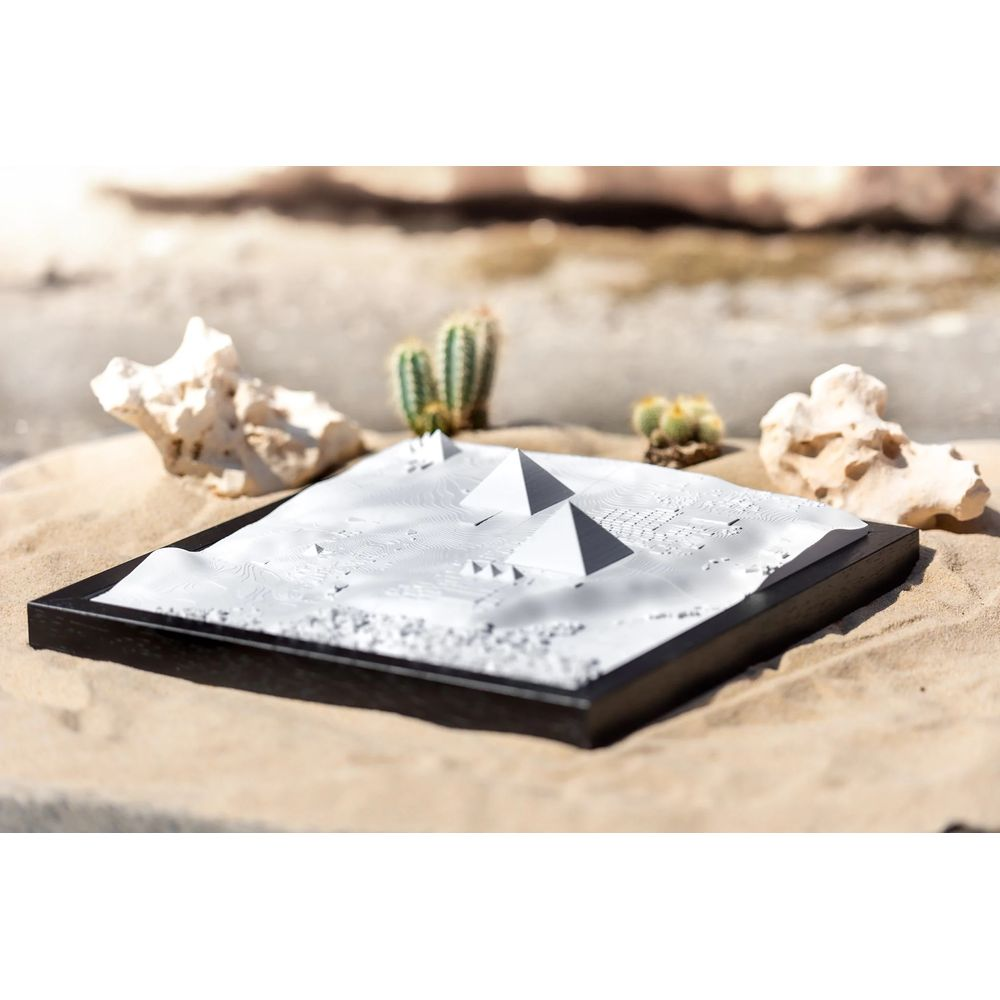 Un modèle blanc de pyramides dans le désert avec cactus et rochers.