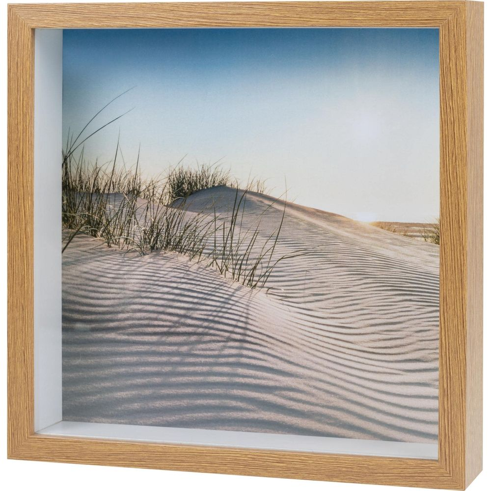 Dune di sabbia con erba e motivi di sabbia ondulata sotto un cielo azzurro limpido.