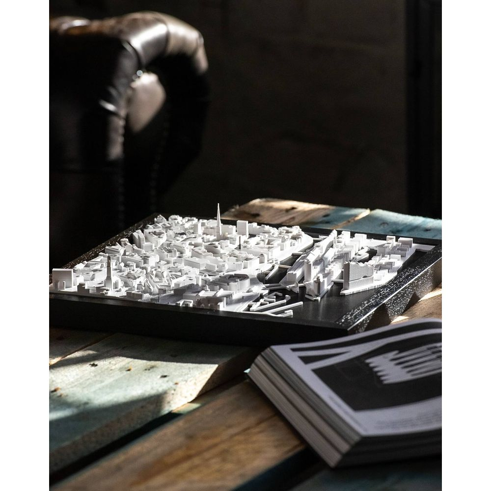 Un modèle de ville blanc avec de nombreux bâtiments et tours sur une table en bois.