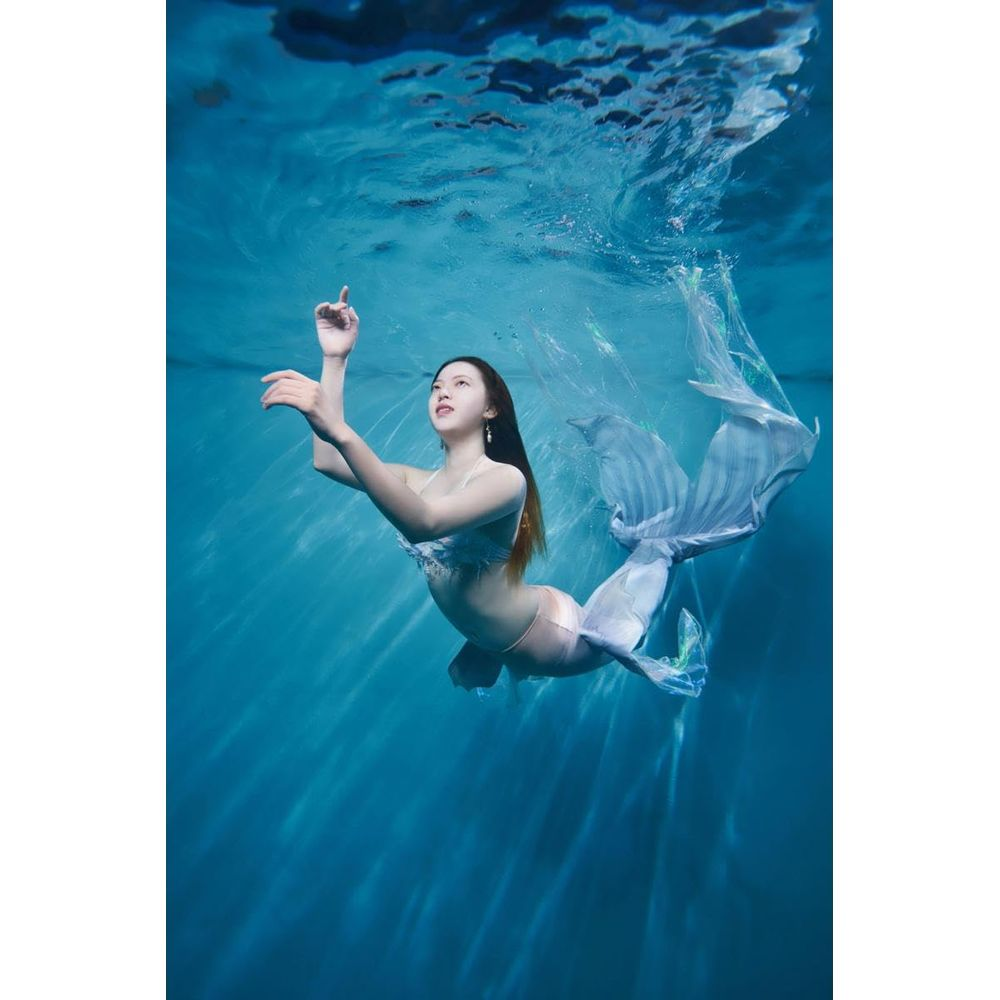 Femme en queue de sirène nageant sous l'eau, lumière filtrant d'en haut.